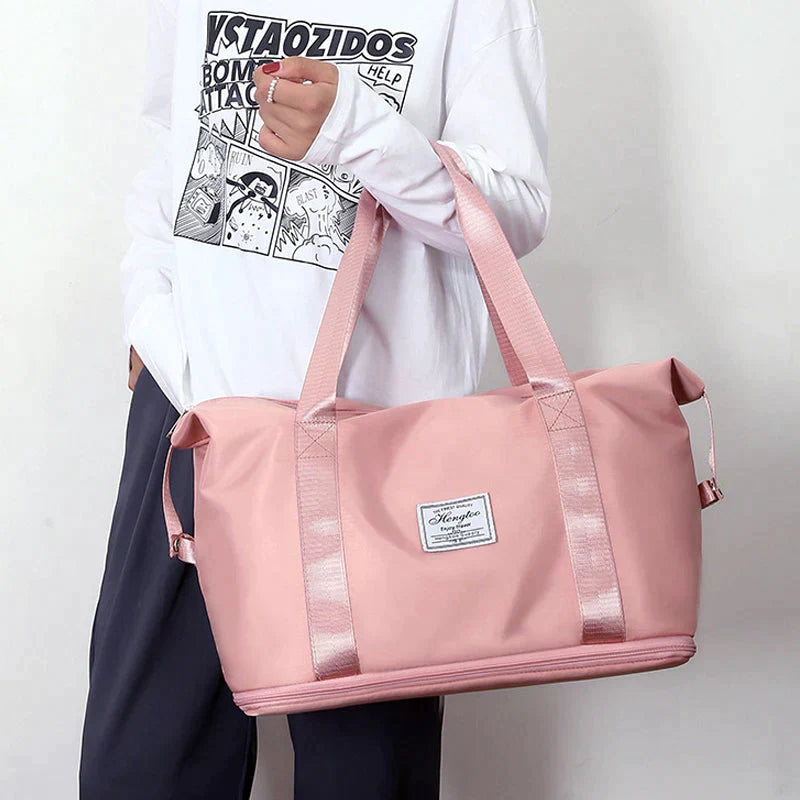 Pink waterproof duffel bag with wide bottom, two long straps, and top zip closure.