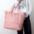 Pink large duffel tote with webbing straps, front patch label, and top zip closure.