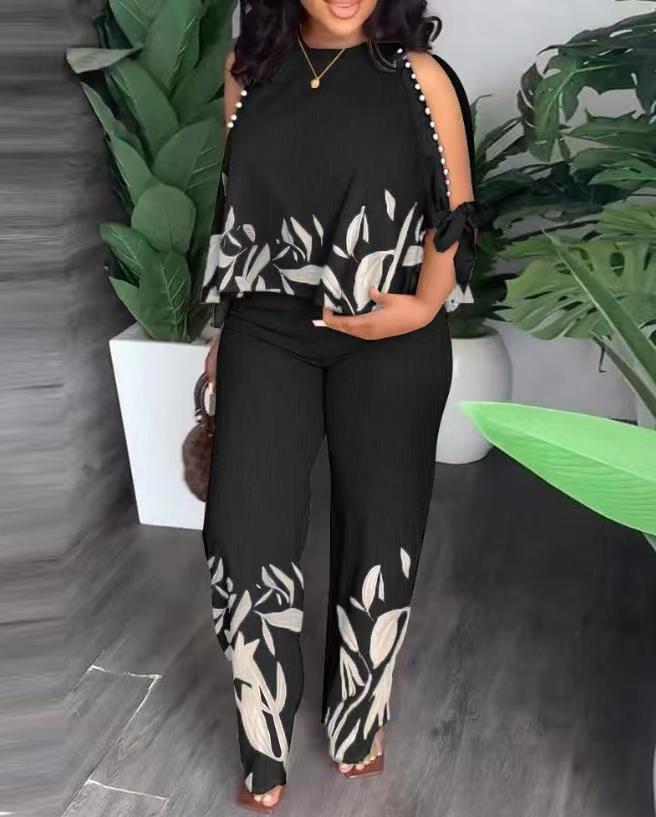 Floral summer jumpsuit in black with sleeveless ruffle shoulders and white leaf print