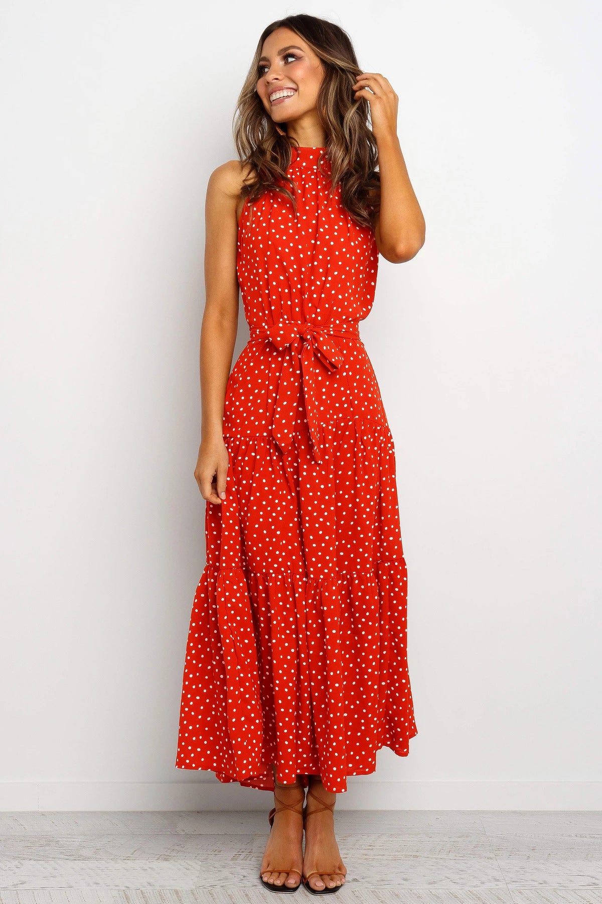 Red sleeveless halter long dress with white polka dots and tied waist