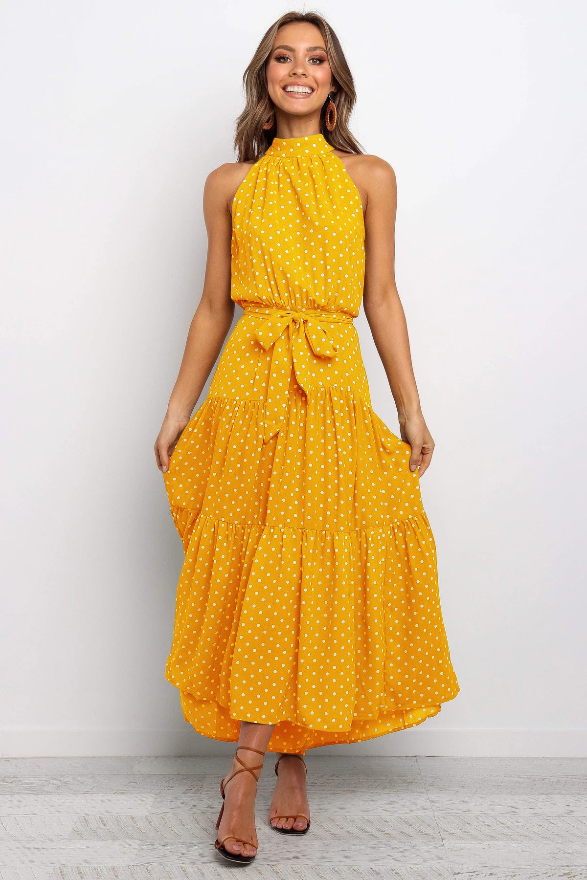 Yellow sleeveless halter long dress with white polka dots and tied waist