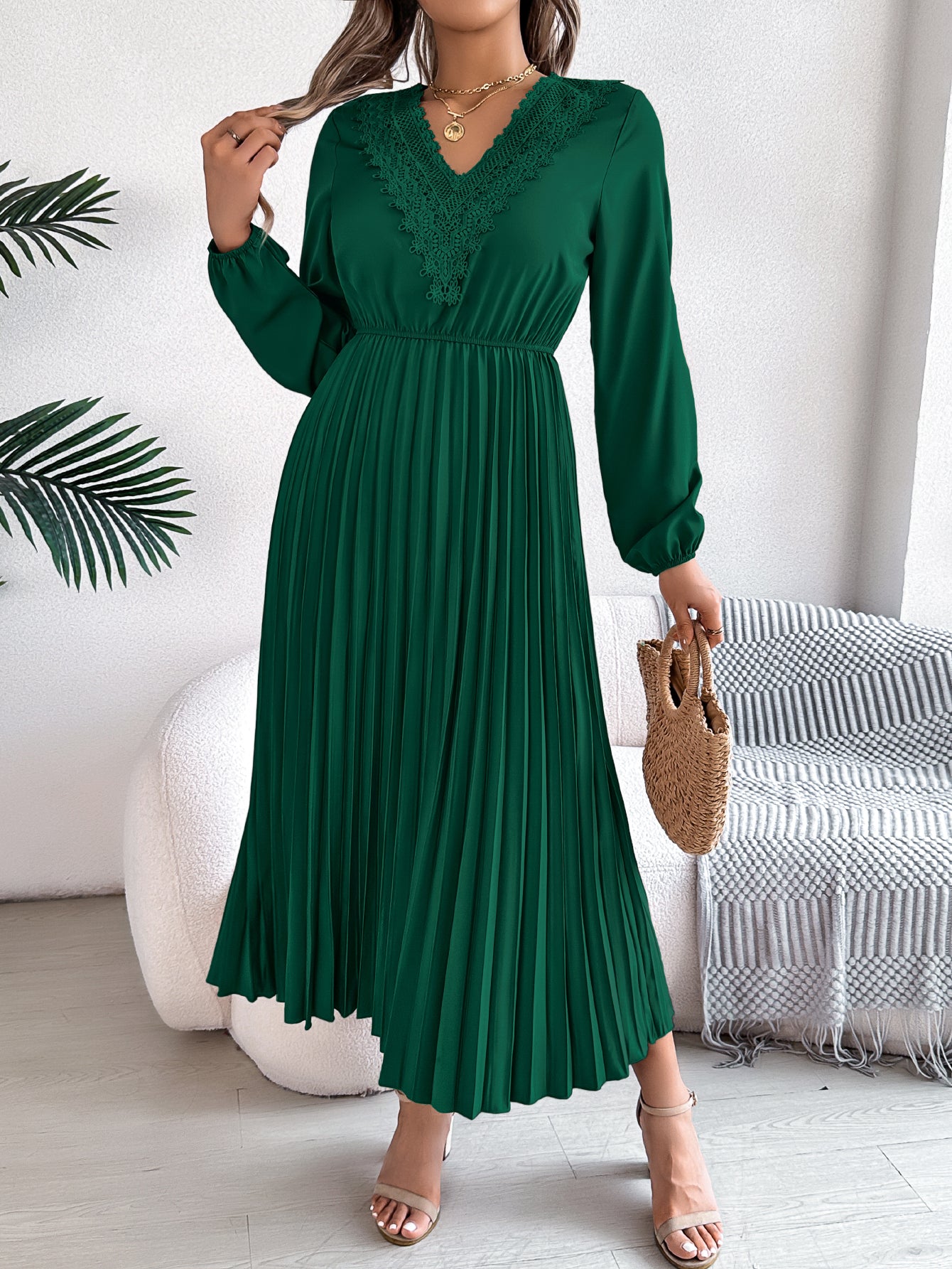 Green pleated midi dress with V-neck lace trim and long balloon sleeves, holds bag