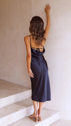 Navy satin midi slip dress with spaghetti straps and cross-back detail.