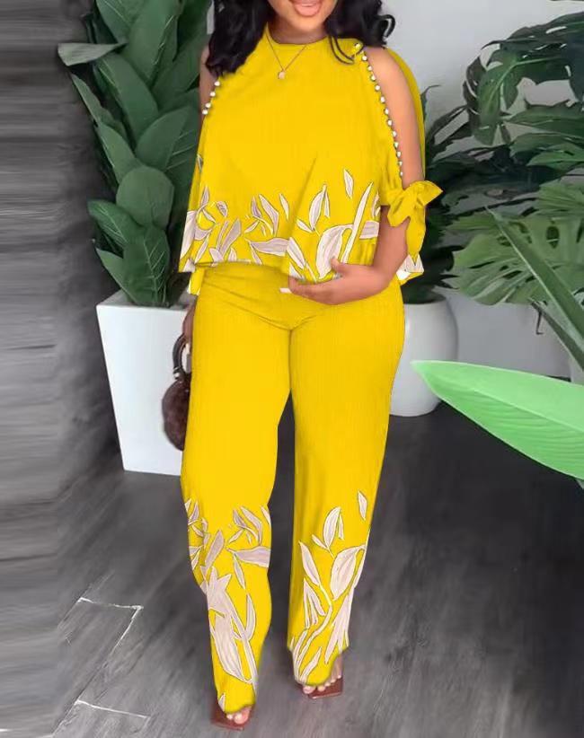 Floral summer jumpsuit in yellow with sleeveless ruffle shoulders and leaf print legs