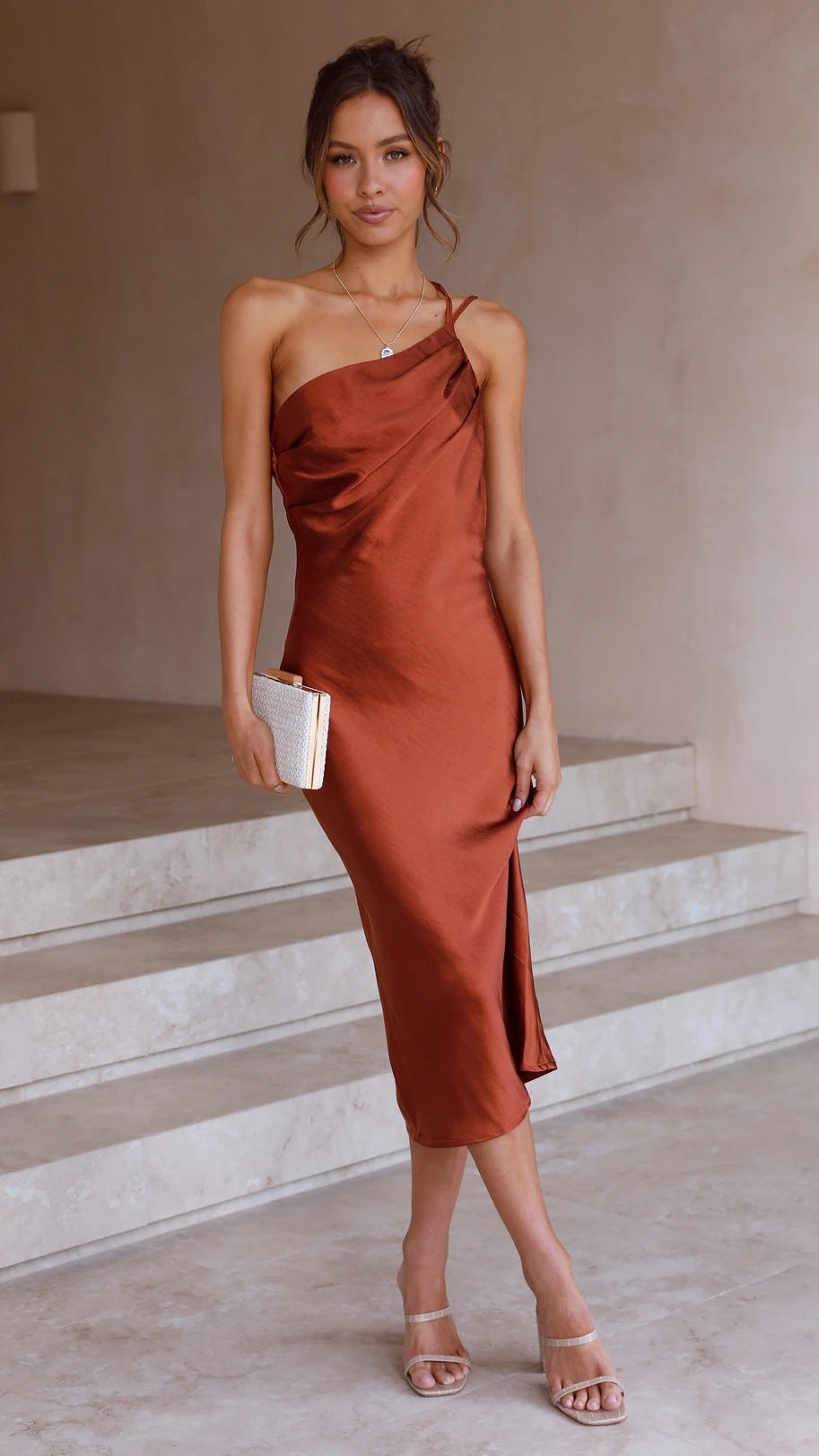 Brown satin midi slip dress with spaghetti straps and draped neckline.