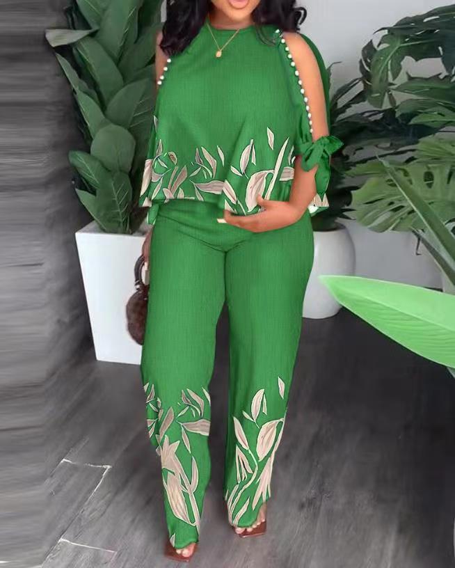 Floral summer jumpsuit in green with sleeveless ruffle shoulders and white leaf print legs
