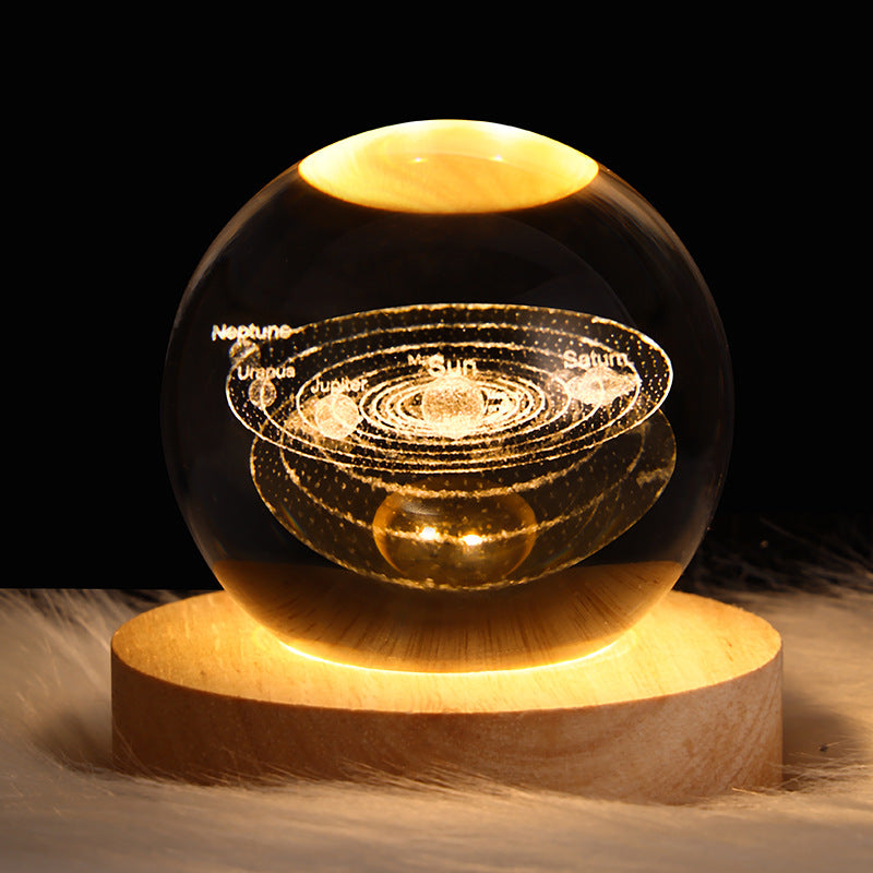 Luminous crystal ball with solar-system light display on a wooden base