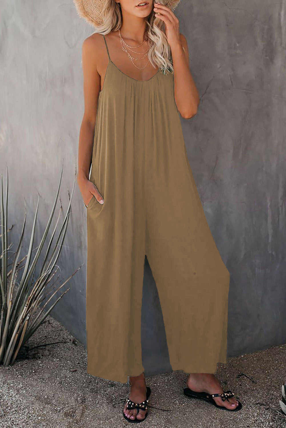 Khaki loose-fitting jumpsuit with thin straps and wide-leg drape.