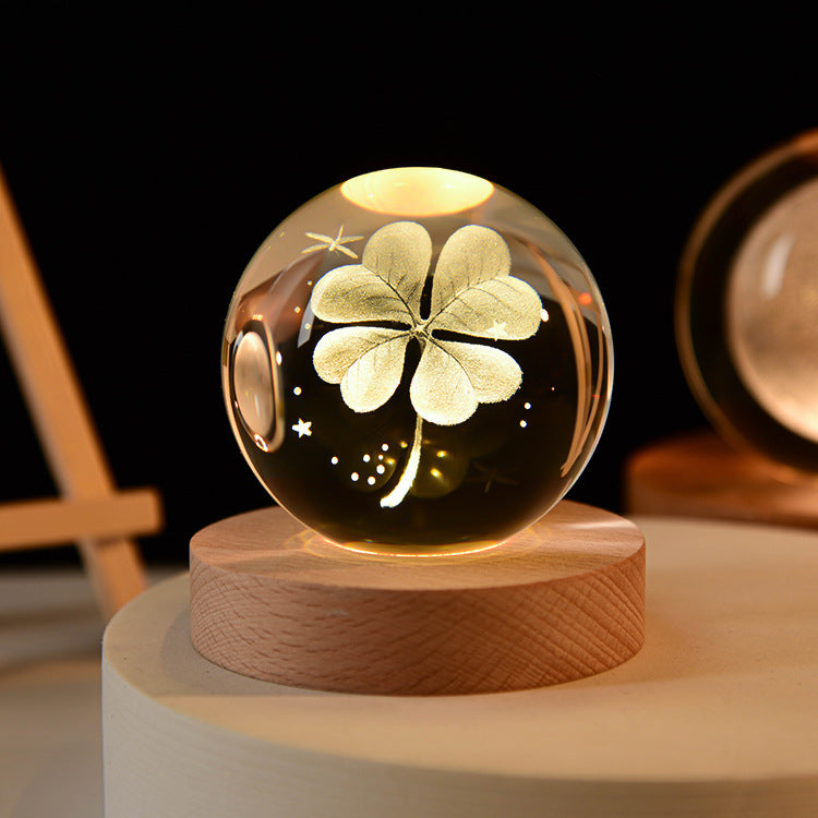 Luminous crystal ball with flower clover light pattern on a wooden base