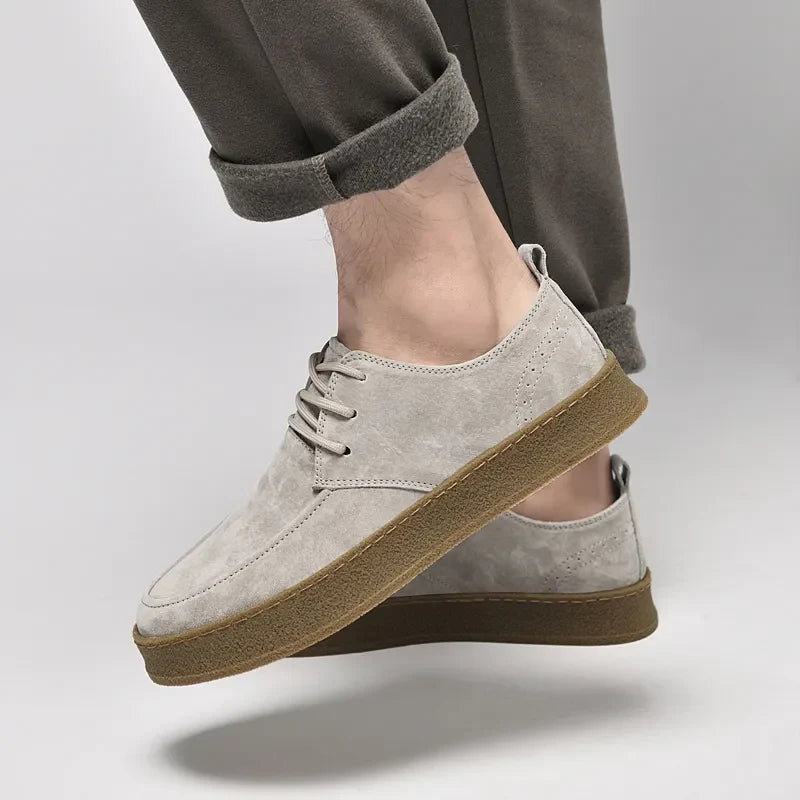 Suede lace-up sneakers with gum rubber sole, worn with pants and foot view