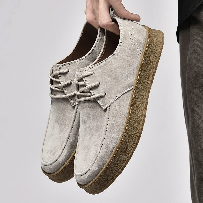Suede lace-up sneakers with gum rubber sole, hand-holding side view