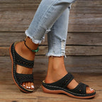 Black slide sandals with cutout stitched detail, two straps, and cushioned sole