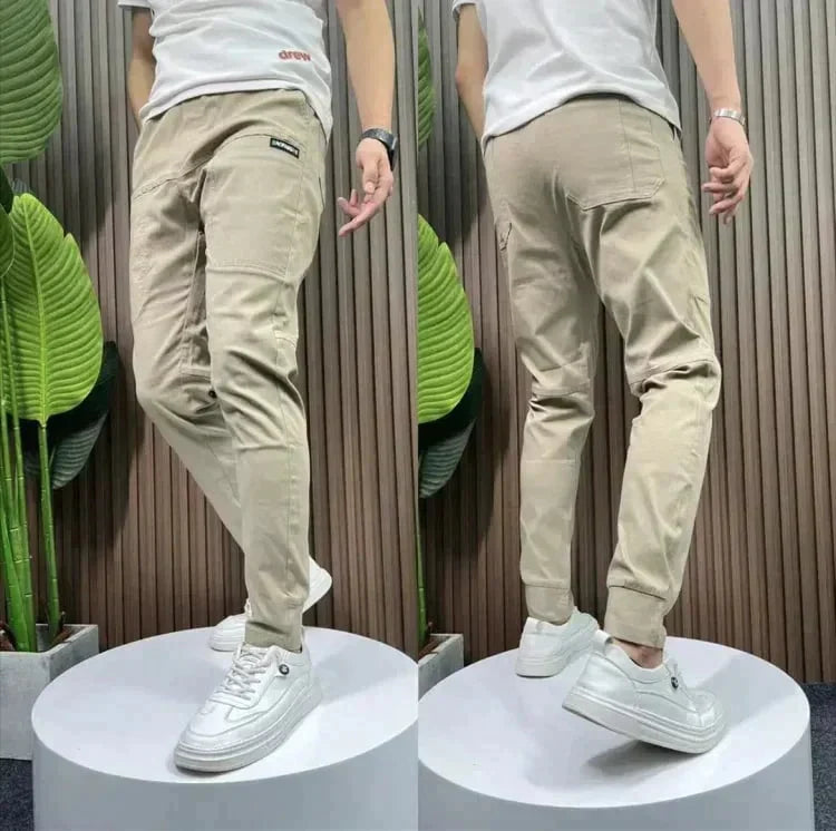 Men's beige casual pants shown from back view, zip fly, tapered legs, pockets