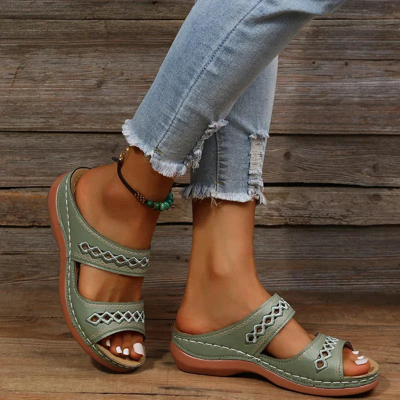 Green slide sandals with cutout stitched detail, two straps, and cushioned sole