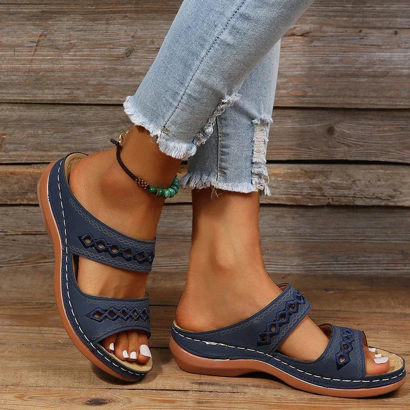 Navy slide sandals with cutout stitched detail, two straps, and cushioned sole