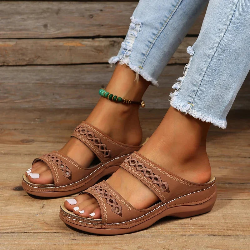 Brown slide sandals with cutout stitched detail, two straps, and cushioned sole