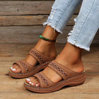 Brown slide sandals with cutout stitched detail, two straps, and cushioned sole