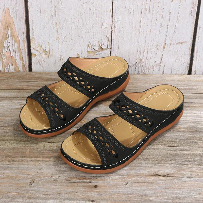 Black slide sandals with cutout stitched detail, two straps, and cushioned sole