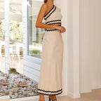 Beige one-shoulder maxi dress with zigzag border at neckline, waist stripe, and hem