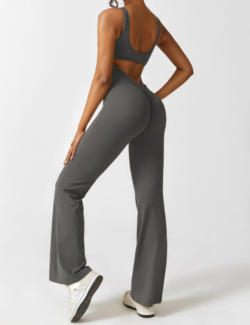 Athletic dark gray jumpsuit with open back panel and flared legs, side view.