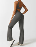 Athletic dark gray jumpsuit with open back panel and flared legs, side view.