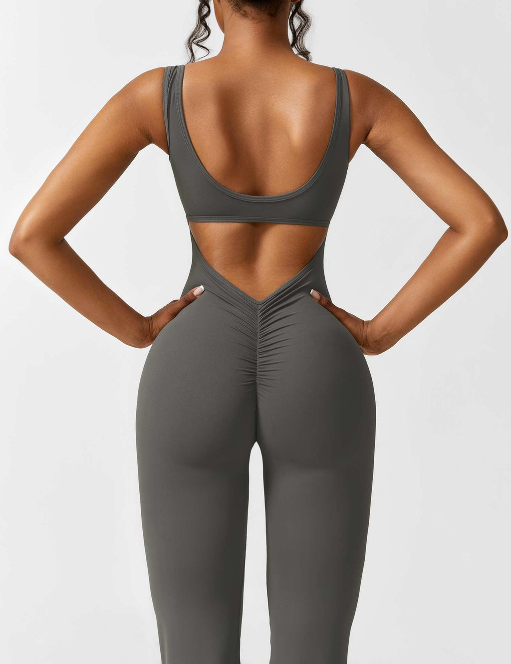 Athletic dark gray jumpsuit with open back cutout and flared pant silhouette.