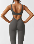 Athletic dark gray jumpsuit with open back cutout and flared pant silhouette.