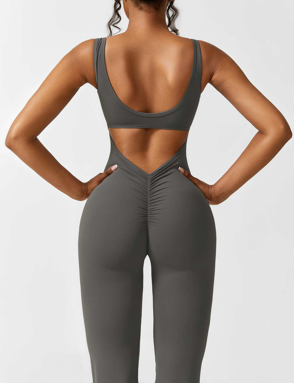 Athletic dark gray jumpsuit with open back cutout and flared pant silhouette.